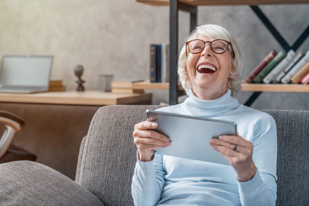 elderly woman laughing with tablet